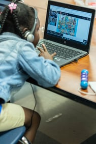 student wearing headphones and working with a virtual tutor on a computer