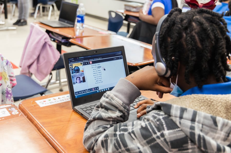 a student sitting in a classroom in a computer, receiving high-impact/high-dosage literacy tutoring from an OnYourMark tutor